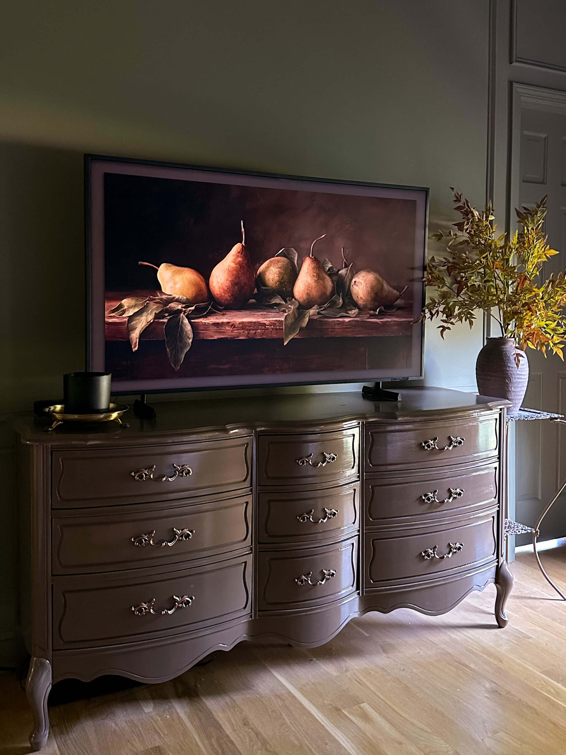 click for moody fall home decor ideas. photo of moody artwork on frame tv, faux fall stems in a dark green room.