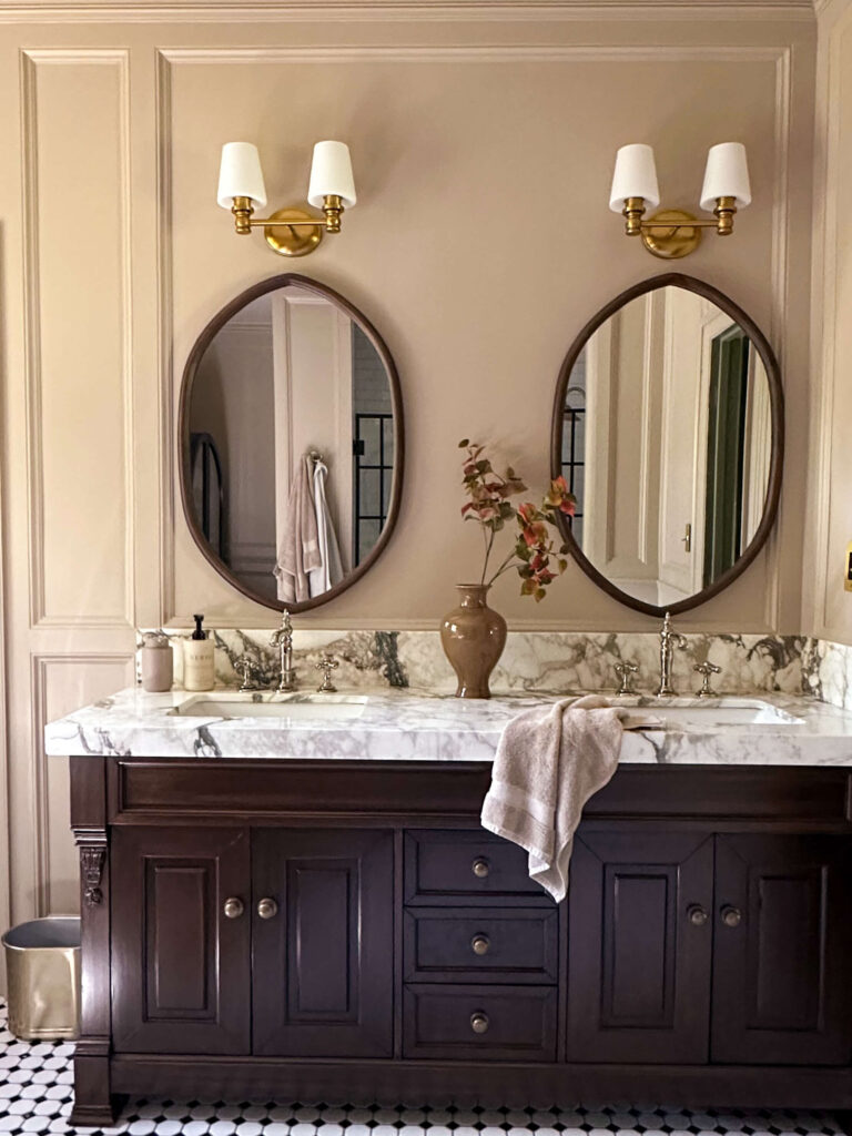 click for my primary bathroom renovation reveal. a rich walnut vanity and calcatta fiorto marble countertops paired with brass and polished nickel fixtures.