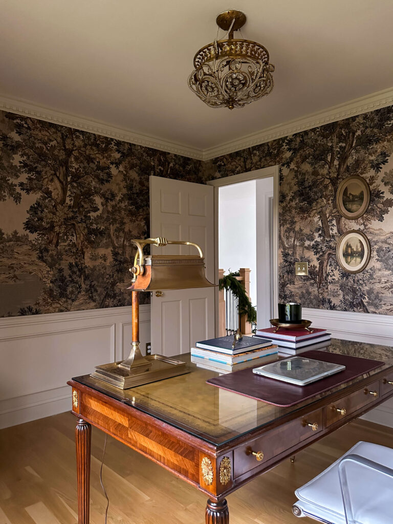 Vintage moody traditional home office with landscape mural, soft cream paint, antique desk and vintage lamp