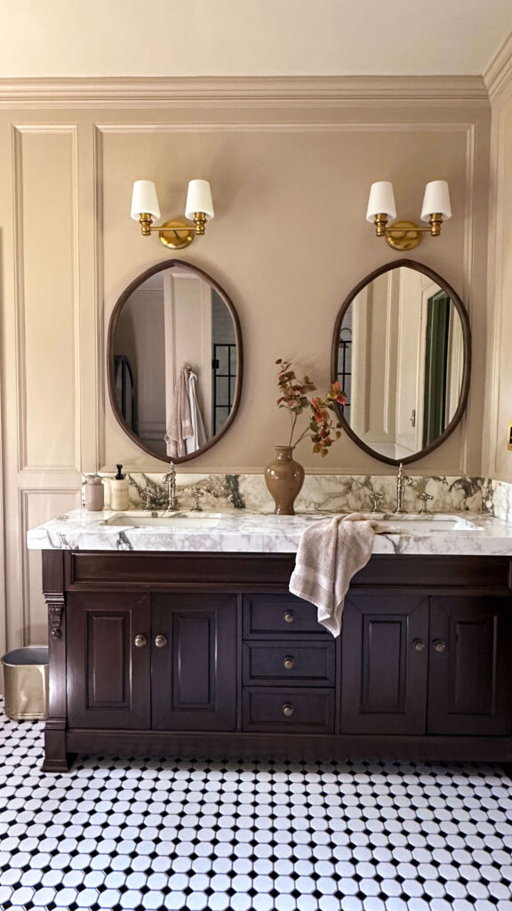 click for my primary bathroom renovation reveal. a rich walnut vanity and calcatta fiorto marble countertops paired with brass and polished nickel fixtures.